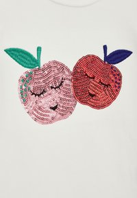 Witte T-shirt met roze en rode pailletten geborduurde appelontwerpen met groene en blauwe bladeren, afgebeeld met lachende gezichten.