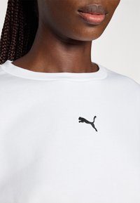 Sweatshirt din bumbac alb cu un logo Puma brodat negru pe piept, cu un design clasic de guler rotund și textură netedă.