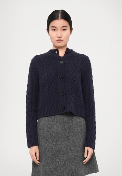 Cardigan in maglia a trecce di colore blu navy con scollo rotondo, dotato di sei bottoni neri sulla parte anteriore e orli e polsini a costine.
