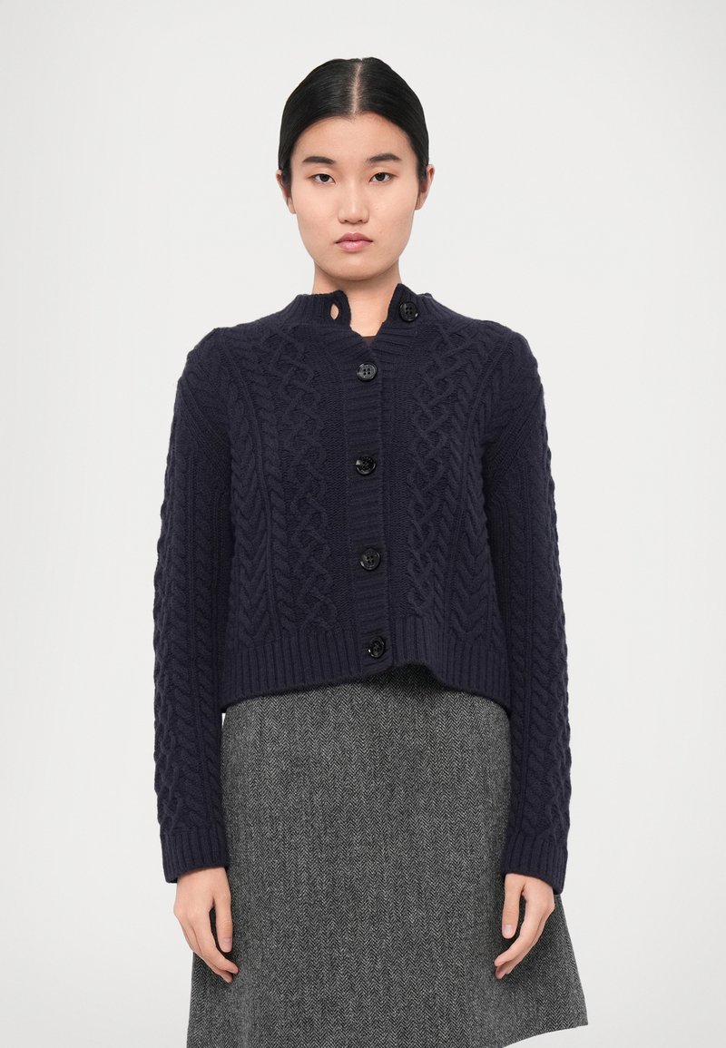 Navy cable-knit cardigan with a round neckline, featuring six black buttons down the front and ribbed hem and cuffs.