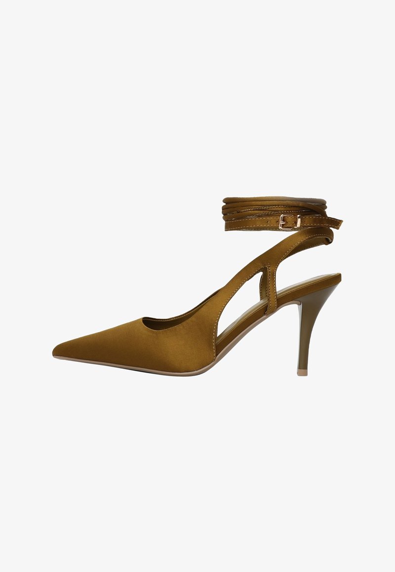 Chaussure slingback à talon haut en daim marron avec un bout pointu, des côtés découpés et une fine bride à la cheville. Dotée d'un talon stiletto modéré.