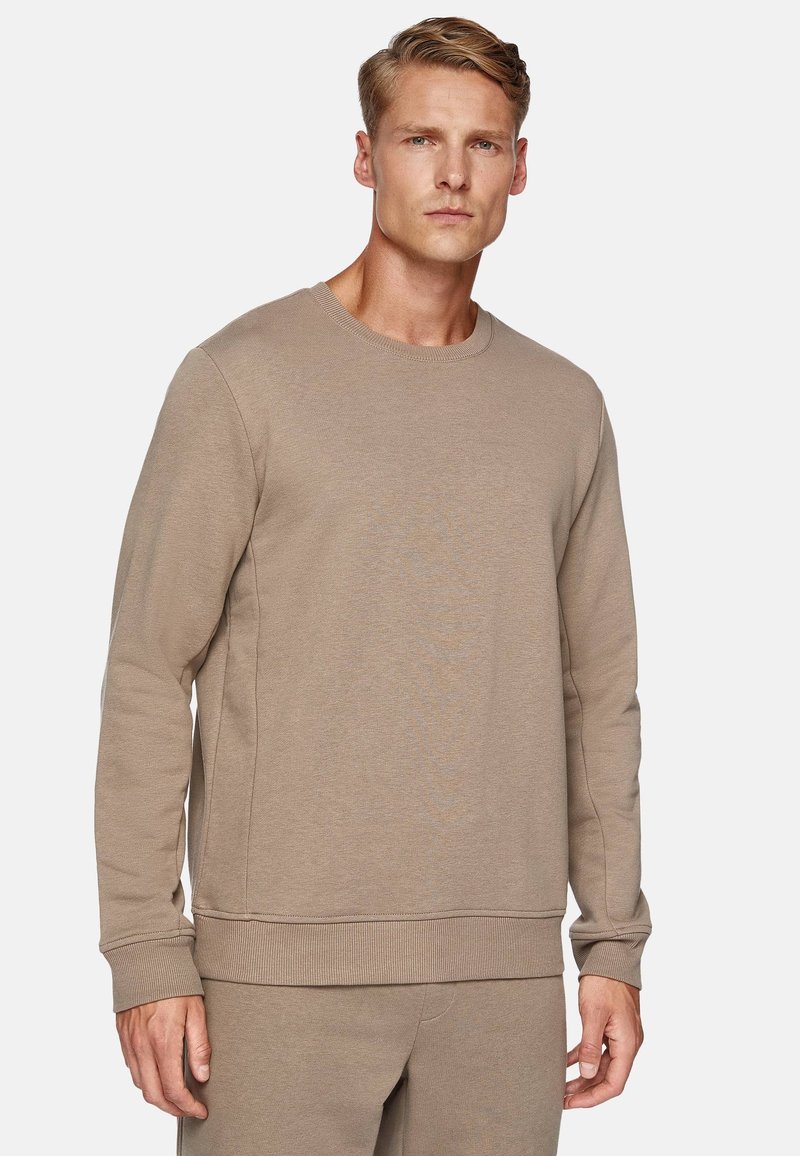 Beige crewneck sweatshirt in soft fabric, featuring ribbed cuffs and hem, with a relaxed fit and seamless design.