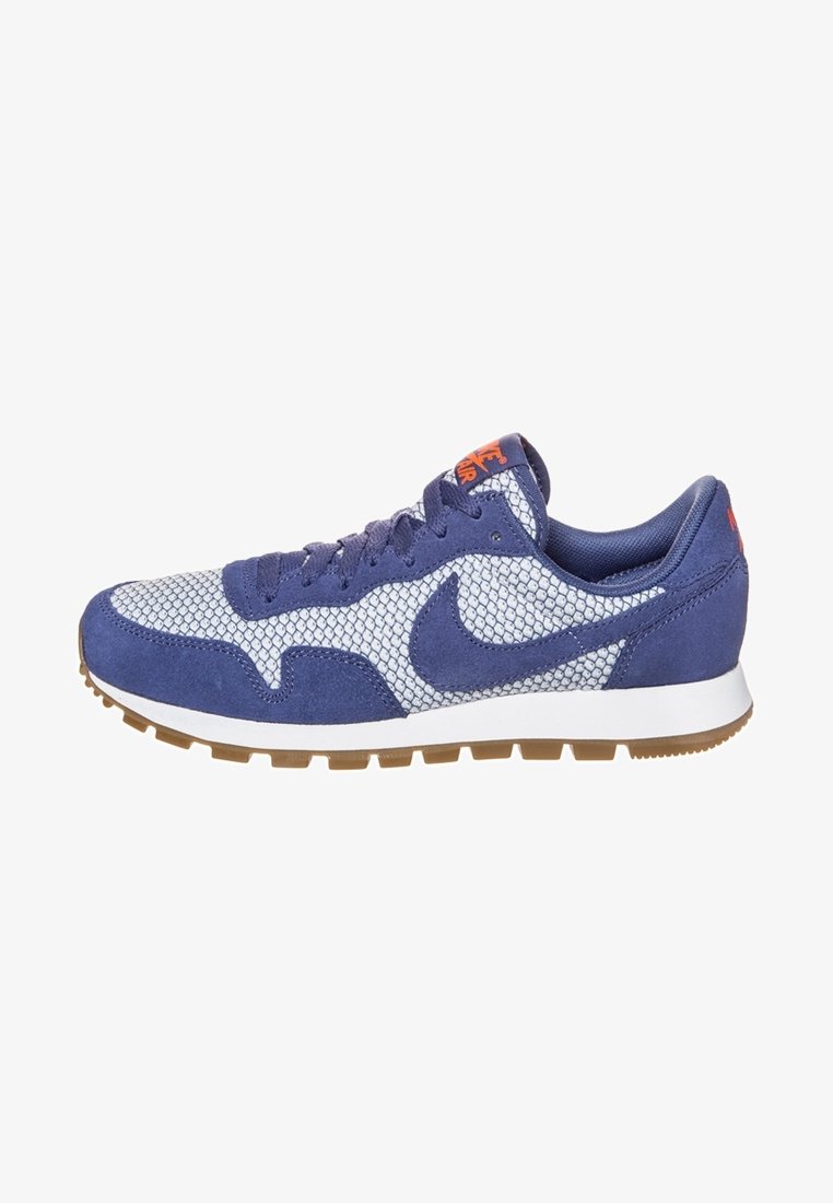 Tmavě modrá semišová a síťovaná sportovní bota s bílou mezipodešví a hnědou gumovou podešví. Obsahuje výrazné logo Nike a oranžové akcenty.