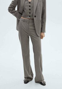 Šedý dobře střižený trojdílný oblek se slim fit vestou s černými knoflíky, širokými kalhotami a strukturovaným sakem s vyztuženými rameny.