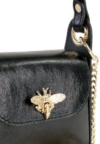 Schwarze Lederhandtasche mit einem goldenen Bienenakzent, einer strukturierten Oberfläche, einem Kettenriemen und einer Klappe mit abgerundeten Kanten.
