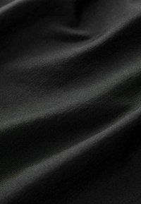 Tela negra con una textura suave, que presenta sutiles estrías. El material parece ligero y se drapea elegantemente, creando pliegues fluidos.