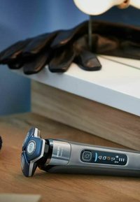 Rasoir Philips avec trois têtes circulaires bleues, un corps argenté et gris, une prise texturée et un panneau de contrôle affichant les réglages et la durée de vie de la batterie.