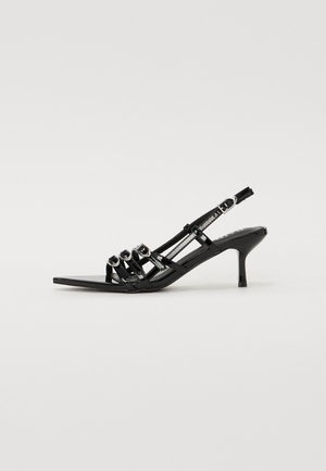 Sorte slingback høyhælte sko med spiss tå, med flere smale stropper og sirkulære detaljer over fronten.