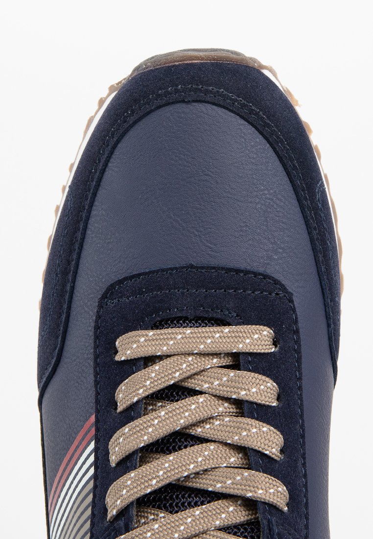 Baskets navy avec une tige en cuir texturé, lacets brun clair avec des éclats, et des accents rayés sur le côté pour plus de détails.