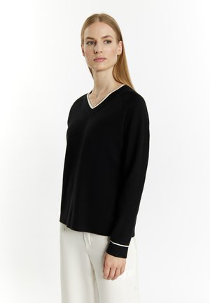 Black V-neck sweater with long sleeves, featuring a cream trim along the neckline and sleeve cuffs; made from soft, fine-textured fabric.