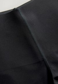 Fekete szövet sima textúrával, középen varrással és kontrasztos cérnázással. Az anyag rugalmasnak és tartósnak tűnik.