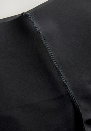 Musta kangas, jossa on sileä pinta, keskellä saumaa ja kontrastiväriset saumat. Materiaali vaikuttaa joustavalta ja kestävältä.