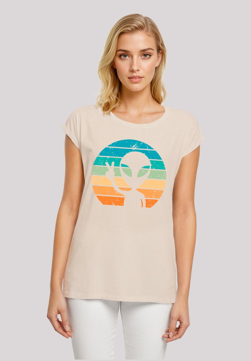 Beige casual T-shirt with rolled sleeves featuring a graphic of an alien against a circular striped design in blue, green, and orange.