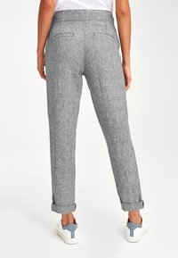 Grijze linnen broek met een gestructureerde afwerking, met opgerolde manchetten en achterzakken. Gecombineerd met witte sneakers met grijze accenten.