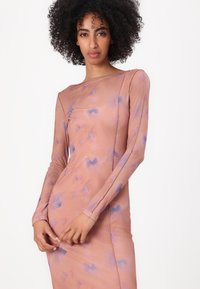 Long-sleeve dress in a soft pink fabric, featuring a floral pattern in blue tones. Fitted design with seamless construction.