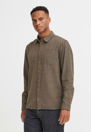 Brown flannel shirt with long sleeves, button-down collar, single chest pocket, and subtle textured pattern. Paired with dark jeans.