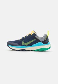 Nike-polkujuoksukengät, joissa on tummansinisestä verkosta valmistettu päällinen, limevihreät yksityiskohdat, keltaiset nauhat ja teksturoitu turkoosi välikerros. Kestävä kumipohja.