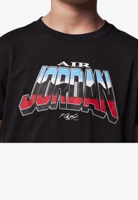 Czarny t-shirt bawełniany z odważną, kolorową grafiką "AIR JORDAN" z niebieskimi, czerwonymi i białymi akcentami oraz podpisem pod słowem "FLIGHT."