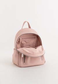 Rosa texturerad läderryggsäck med en rundad design, topphandtag och dubbel dragkedjestängning. Interiören har ett ficka med dragkedja och ett rymligt fack.