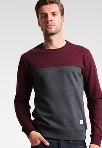 Sudadera para hombre, parte superior color burdeos y parte inferior gris, mezcla de algodón, cuello redondo, puños y dobladillo acanalados, etiqueta de logo pequeña en el lado inferior.