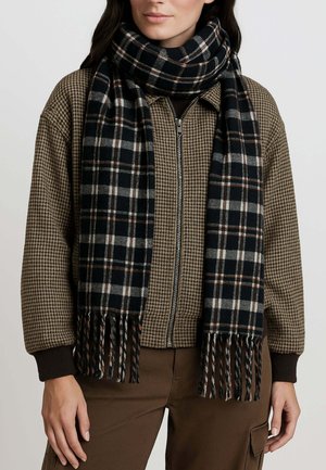 Sciarpa a quadri nera e grigia con estremità frangiate, realizzata in un materiale morbido, indossata sopra un giubbotto marrone a motivo houndstooth.