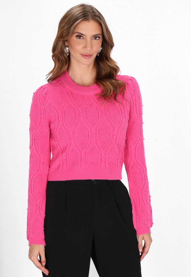 Heldroze cropped trui met een textuurpatroon en versieringen, met een ronde hals en lange mouwen, gecombineerd met zwarte broeken.