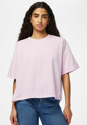 Lys lyserød oversized t-shirt lavet af blødt stof, med korte, brede ærmer og rund halsudskæring, kombineret med blå denimjeans.