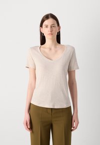 Tricou bej cu mânecă scurtă și guler în V, realizat dintr-un material ușor, asortat cu pantaloni verzi măslinii. Design simplu și versatil.