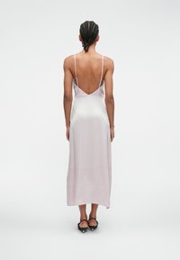 Ροζ σατέν φόρεμα slip με λεπτές τιράντες, σχέδιο V στην πλάτη, μήκος μέχρι το πάτωμα και απαλό υφή. Συνδυασμένο με μαύρες εσπαντρίγιες με λουριά.