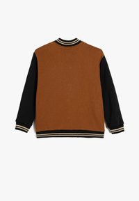 Brun og sort varsityjakke med kontrasterende ærmer, ribbet krave og stribet bund. Blødt stof med et afslappet design.