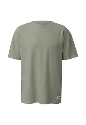 Hellolivgrünes T-Shirt mit kurzen Ärmeln und Rundhalsausschnitt, mit einem kleinen rechteckigen Markenlabel nahe dem unteren Saum auf der rechten Vorderseite.