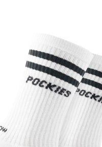 Calze bianche a costine con due righe nere vicino alla cima e la parola "POCKIES" tessuta sotto le righe.
