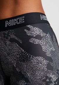 Czarne leginsy Nike mają fakturowany wzór z małymi białymi kropkami tworzącymi efekt gradientu. Elastyczny pas z logo.