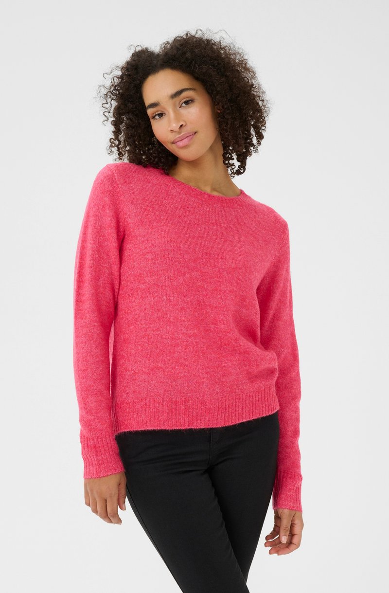 Lyserød strikket sweater med rund hals, lange ærmer og ribbede manchetter. Teksturen synes blød og let fnugget, designet til afslappet brug.