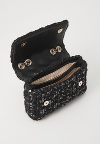 Clutch nera con paillettes e dettagli dorati, dotata di chiusura a scatto. L'interno presenta due scomparti e una fodera in tessuto.