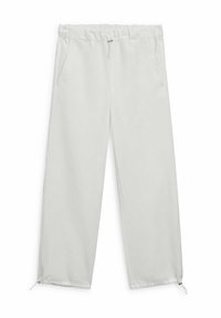 Lichtgrijze, loszittende broek met elastische tailleband en trekkoord. Voorzien van zijzakken en ritsen bij de enkels. Gladde stoftextuur.