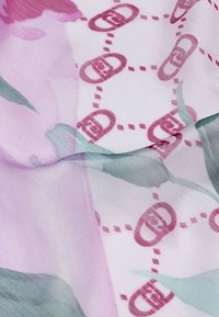 Tessuto trasparente con motivo floreale in tonalità di rosa e verde; presenta motivi ovali ripetuti e dettagli a pois. Texture liscia e leggero.