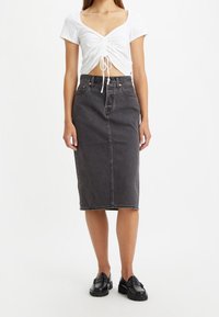 Svart denim midi kjol med rak skärning, med en framseam, texturerad yta och klassisk femficksdesign. Matchad med en vit kortärmad topp.