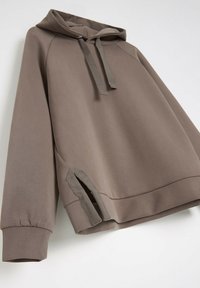 Brązowa hoodie z kapturem o luźnym kroju, z kieszenią kangurzą i bocznymi rozcięciami. Wykonana z miękkiego, teksturowanego materiału z trokami.