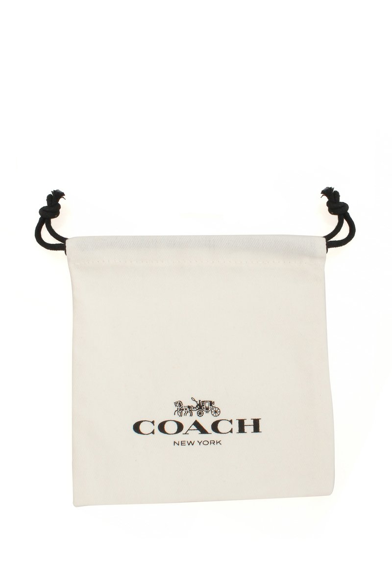 Sac en toile blanc avec cordon de serrage et accents noirs. Présente le logo "COACH NEW YORK" en noir, avec une illustration détaillée au-dessus du texte.