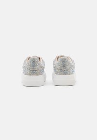 Sneaker scintillanti e iridescenti con suola in gomma bianca, caratterizzate da una tomaia texturizzata ricoperta di ornamenti multi-colorati e scintillanti.