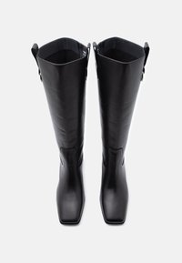 Mustad mustad põlvekõrgused saapad ruudukujulise varbaga, siledast materjalist, sirge disainiga ja ülemises osas on paelad.