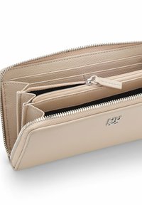Beżowy skórzany portfel o teksturowanym wykończeniu, wyposażony w wiele przegródek, zapięcie na zamek błyskawiczny oraz srebrne akcenty metalowe.
