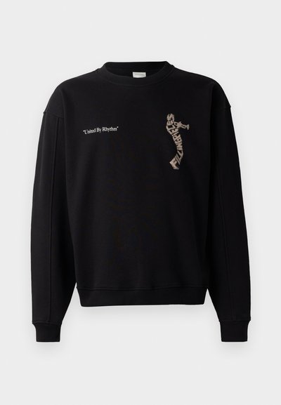 Felpa nera dal fit rilassato; presenta un collo rotondo, maniche lunghe e la scritta "United By Rhythm" con un design grafico frontalmente.