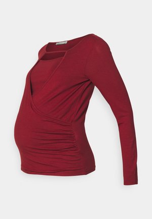 Långärmad gravid topp i djup röd färg, med en inslagningdesign, sidofodring och rundad halsringning. Mjuk, stretchig tyg.