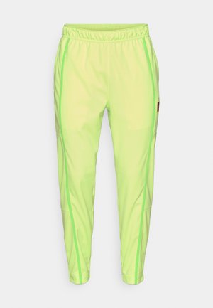 Neongröna träningsbyxor med strukturerad yta, med sid sömmar i en mörkare grön nyans, resårmidja och muddar vid anklarna.