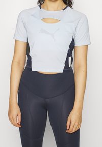 Ljusblå kortärmad sporttop med skärddetalj, parat med mörkblå högmidjade leggings. Båda har figurnära passformer och släta texturer.