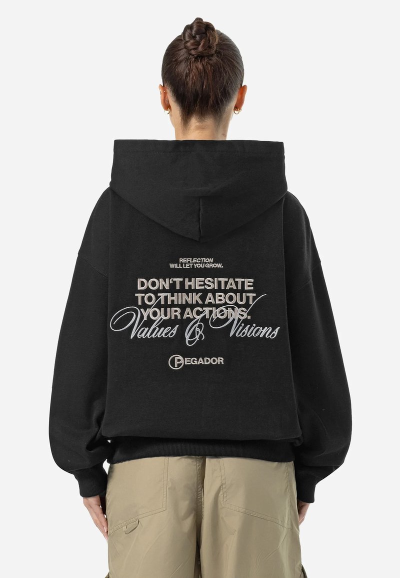 Svart oversized hoodie med ett stort tryck på baksidan. Har text i vitt och silver, samt varumärket "Pegador" längst ner.