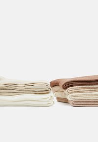 Staplade strumpor i beige, krämfärgad och brun. Stickad textur med vikta kanter. Mjuk material; rena linjer; minimalistisk design.