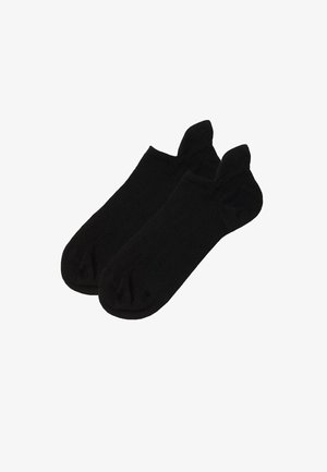Paar schlichte schwarze Knöchelsocken, flach auf weißem Hintergrund ausgelegt.